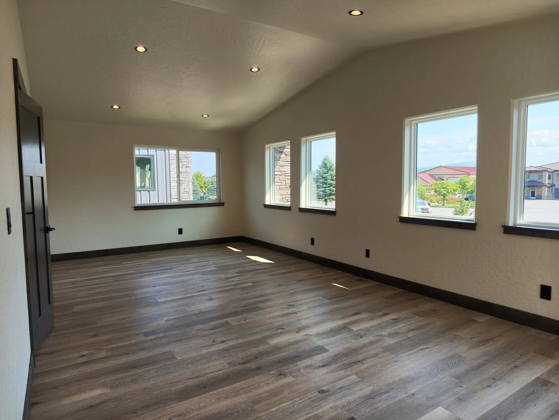 Bright conference room with windows on two walls and wood-look plank flooring.