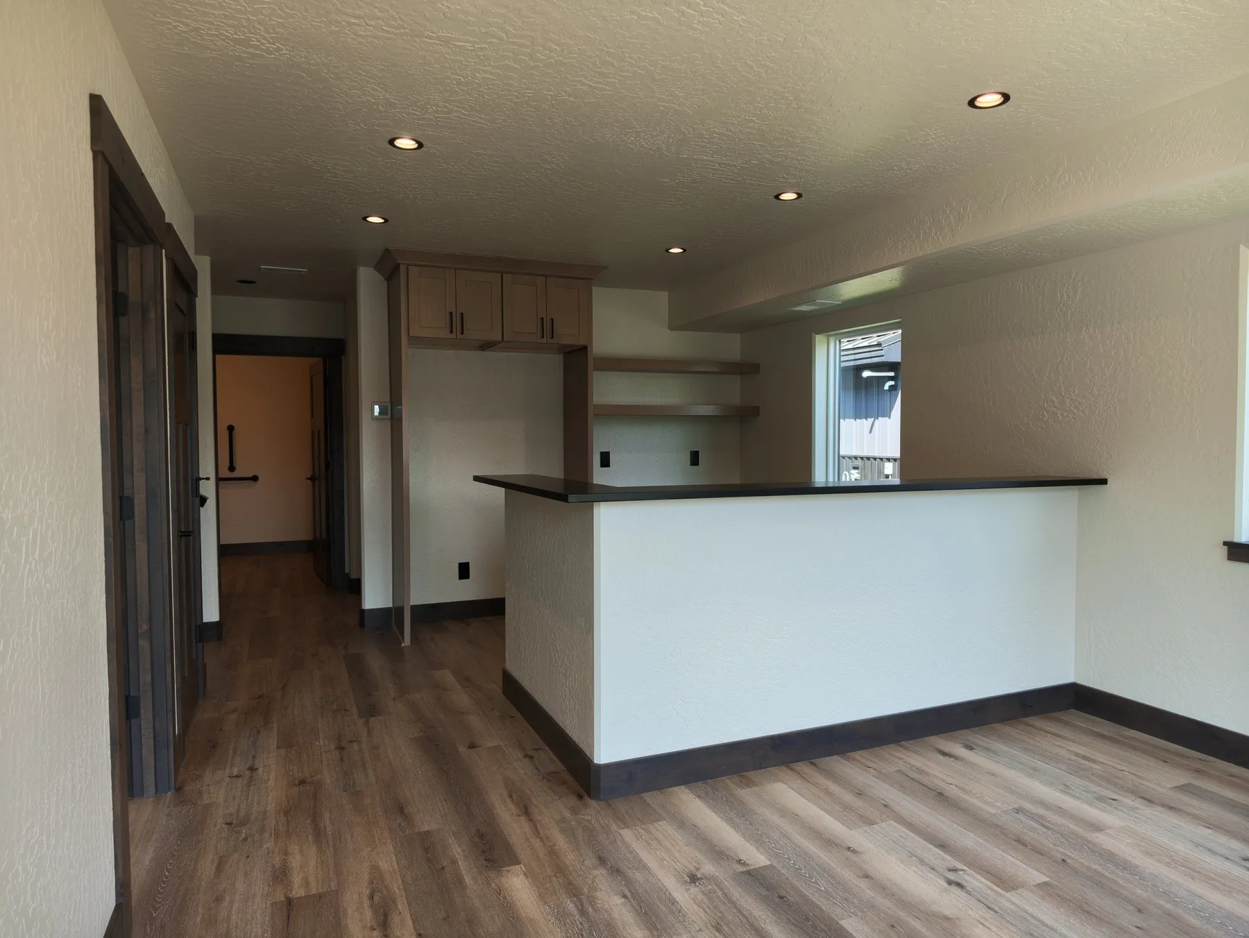 Reception area with a white front counter, wood-look plank flooring and a hallway leading back to the offices.