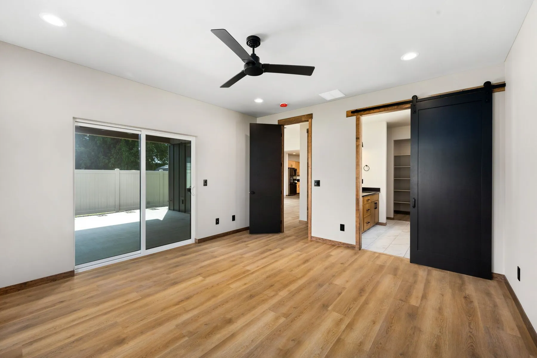 Primary bedroom with a sliding glass door to the patio and a black barn door opening to the bathroom.