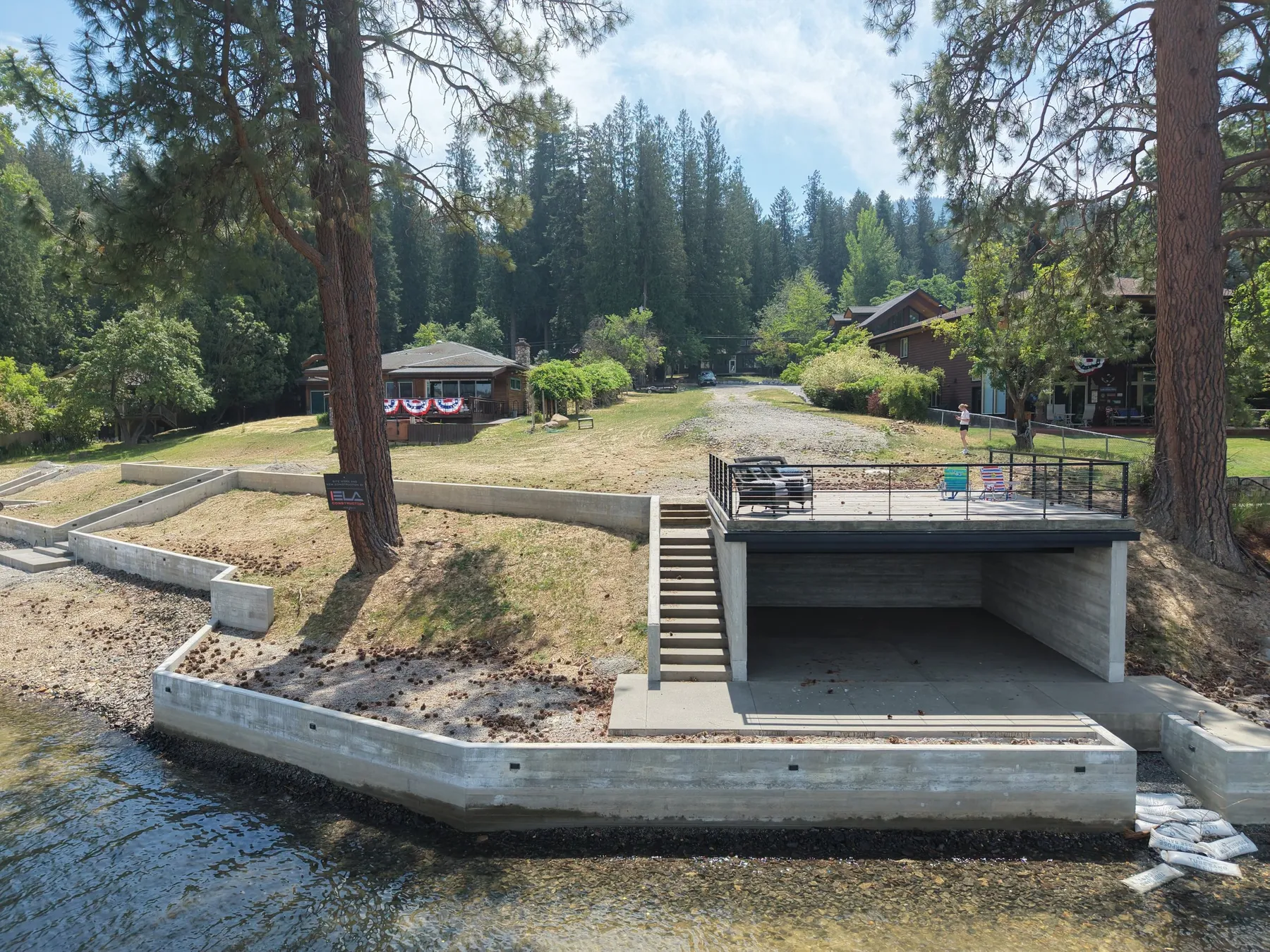 Finished concrete seawall on the Hayden Lake shoreline with a cabana built into the wall and a railed deck on its roof.