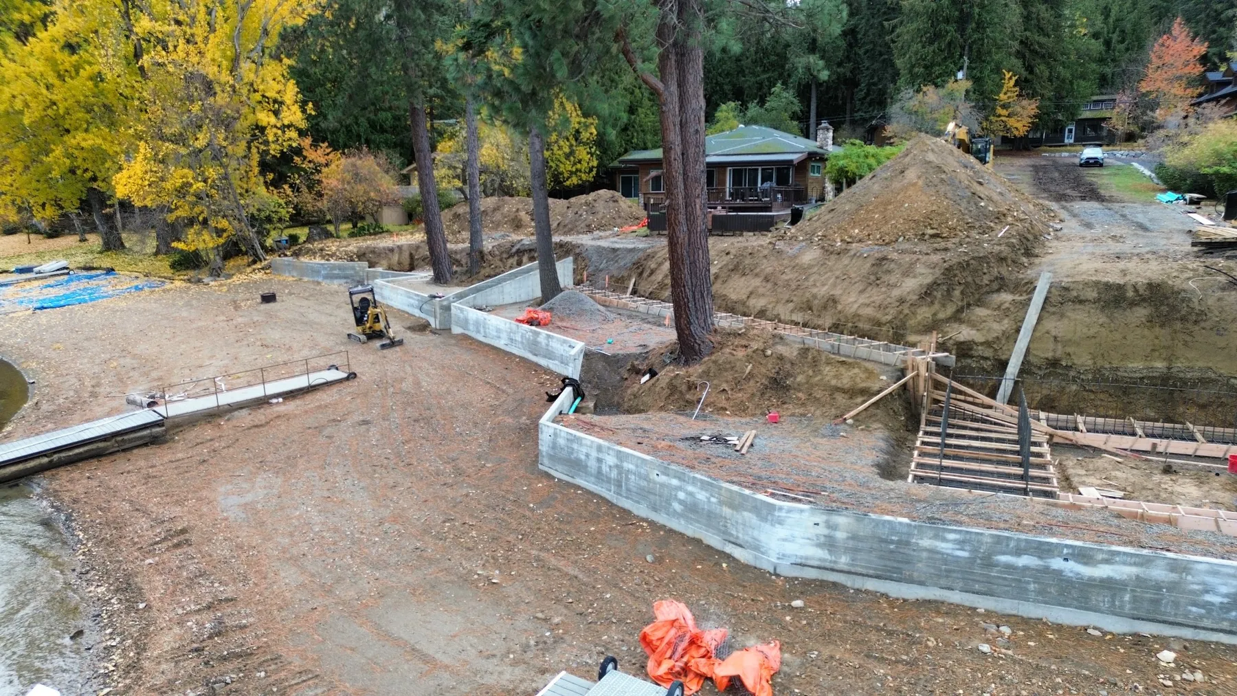 Seawall and cabana under construction, with concrete walls, formed stairs and graded fill along the beach.